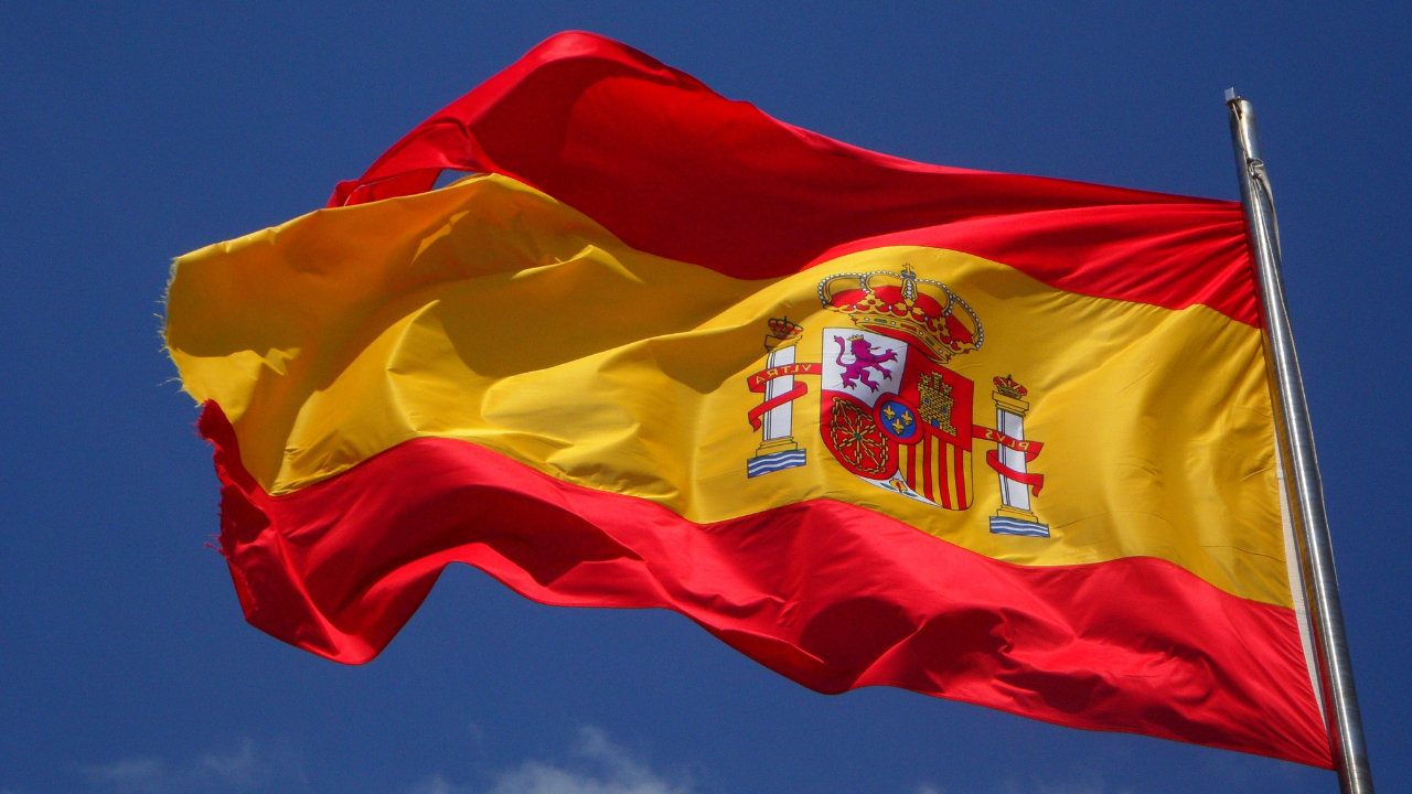 Spanish flag waving in the wind under a clear blue sky.