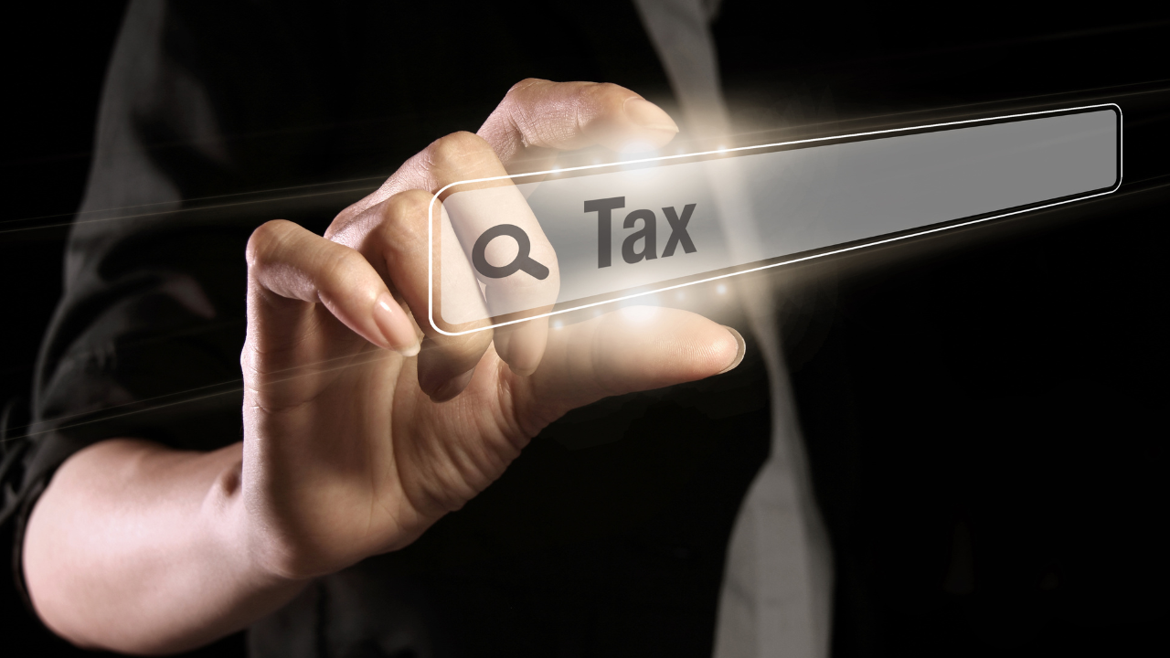 Hand pointing at digital search bar with the word 'Tax', symbolising tax optimisation research