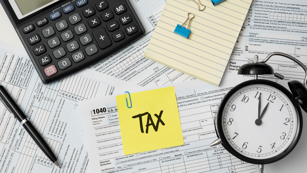Tax forms, calculator, clock, and a sticky note labeled "TAX" representing international tax planning and the use of double taxation treaties in Spain.