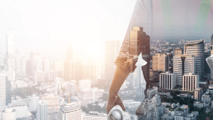 Double exposure of a construction manager holding architectural blueprints merged with a modern city skyline, symbolizing off-plan property development and future value.